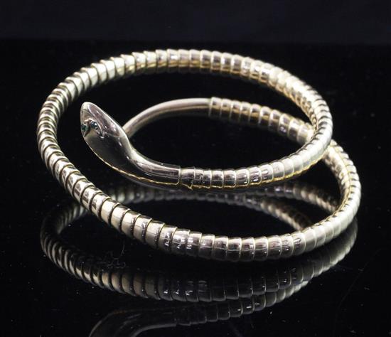 A 9ct gold serpent bangle with emerald set eyes.